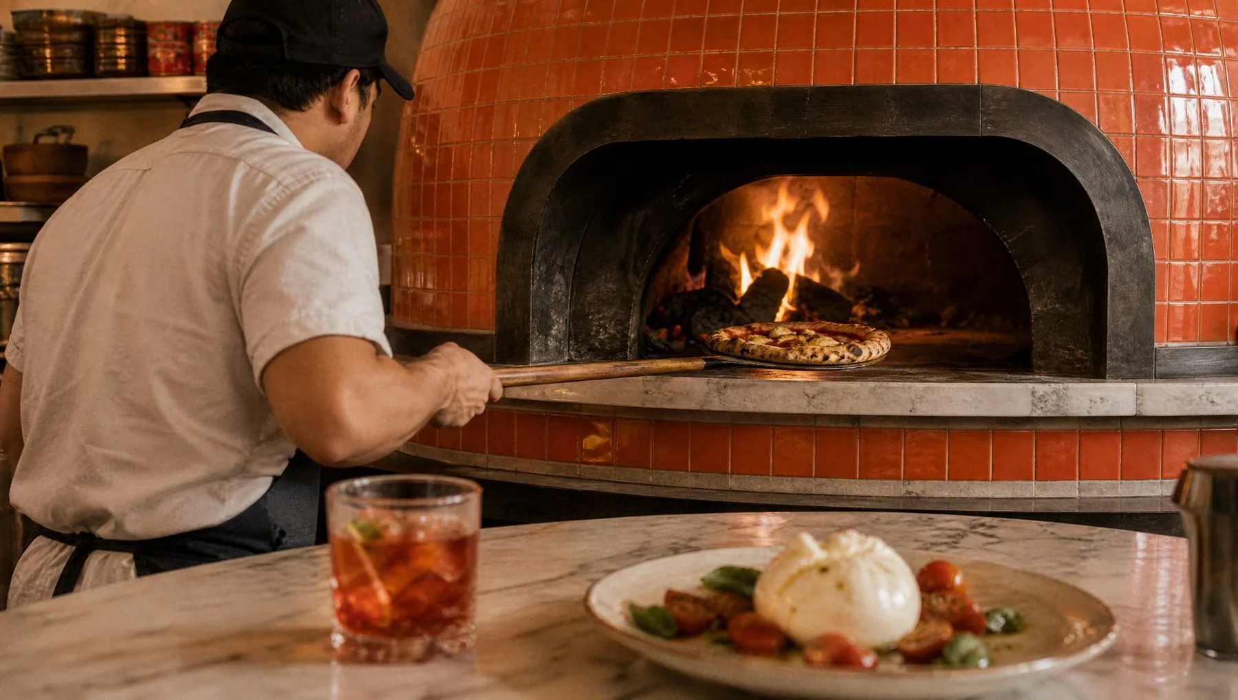 The pizzaiolo at the tiled wood-fired oven