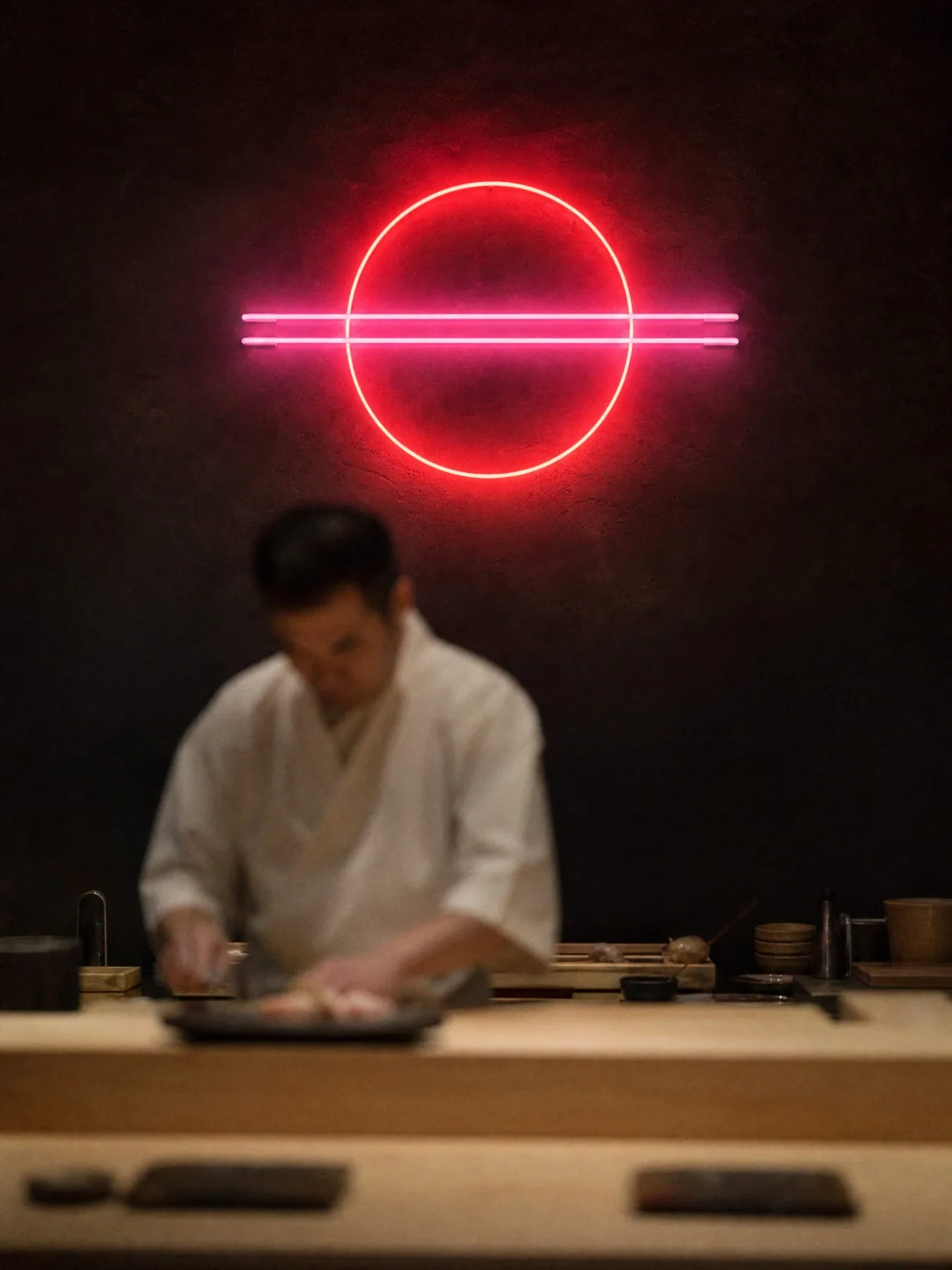The neon ring and chopsticks above the chef